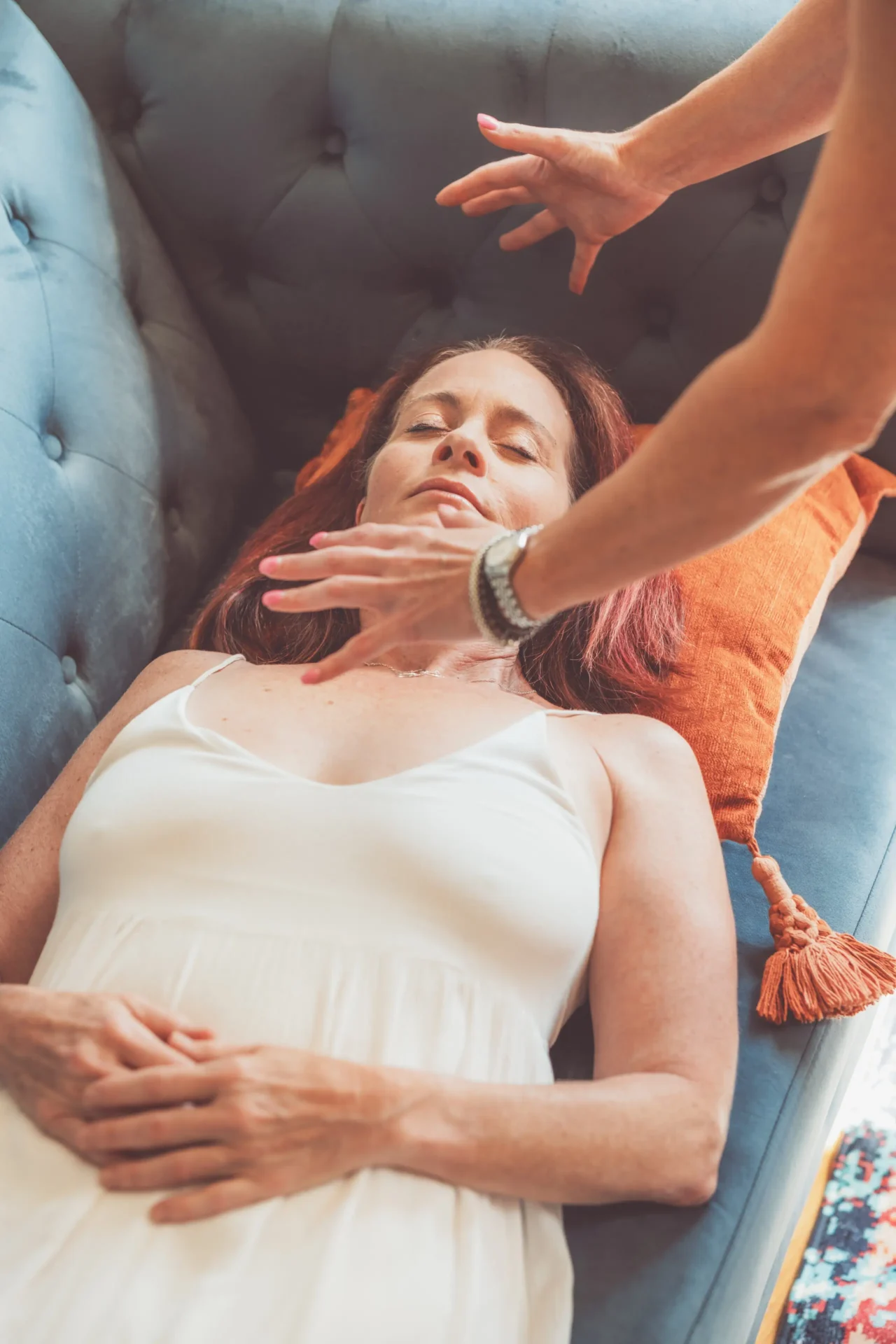Woman lying down, receiving a healing touch on her forehead.