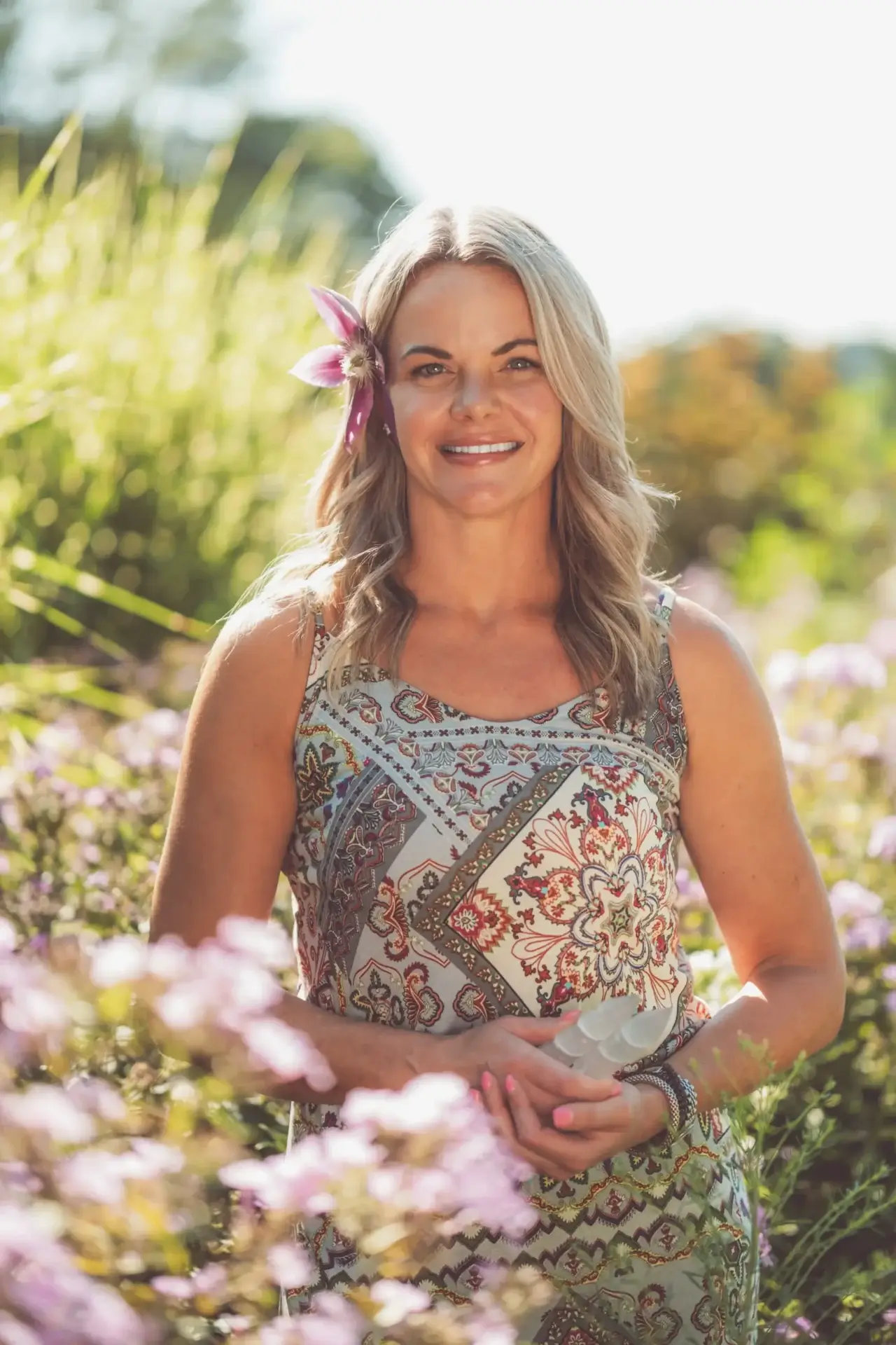Woman in floral dress smiling in garden.